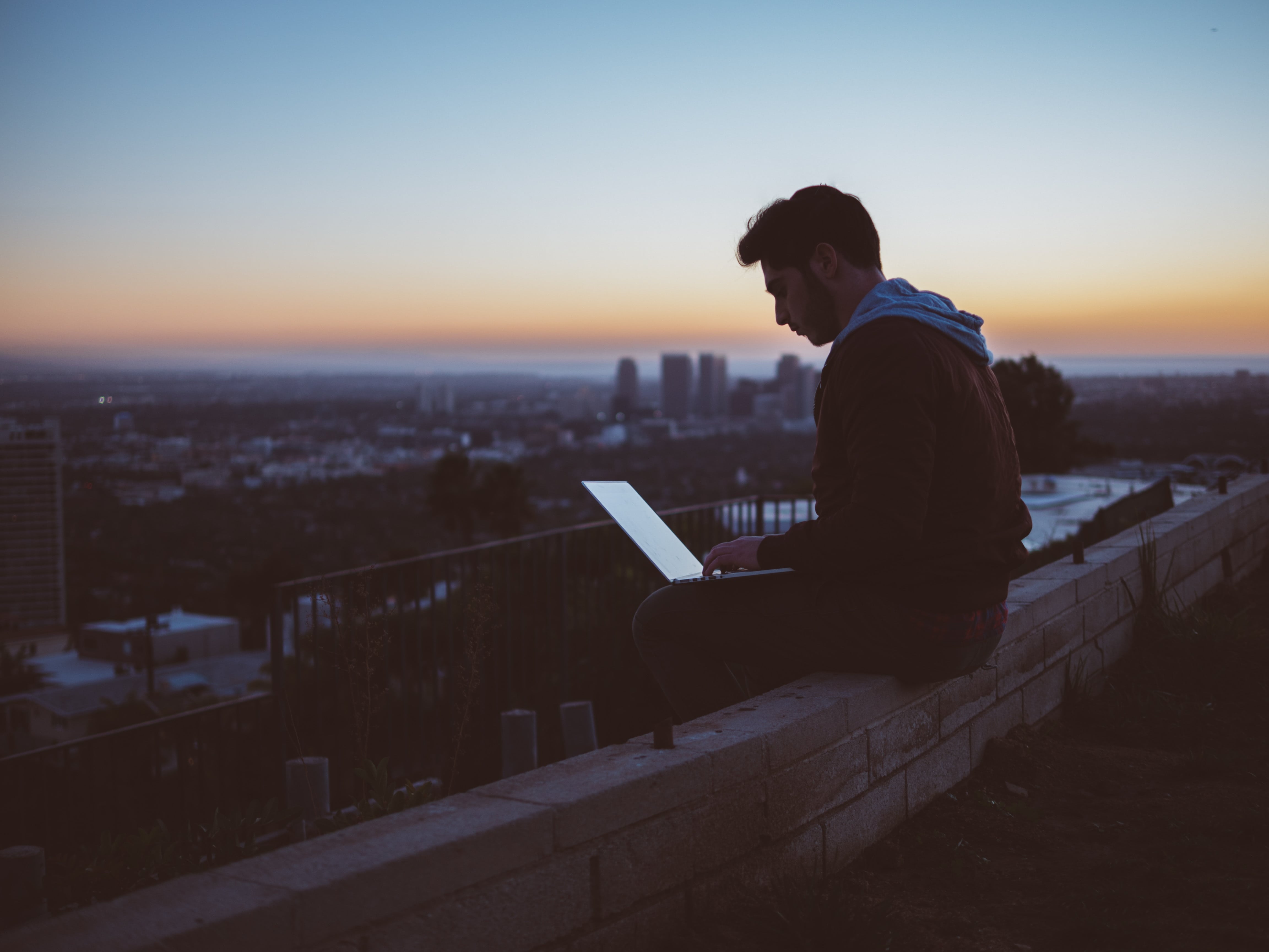 A man working on a computer from a rooftop.